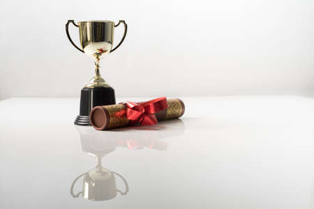Golden trophy and graduation scroll on white table.Education concept.の写真素材