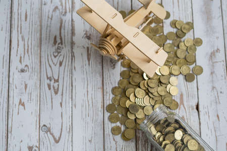 Wooden Airplane toy and jar of coins on vintage wooden table with copy space.Travel concept.の写真素材