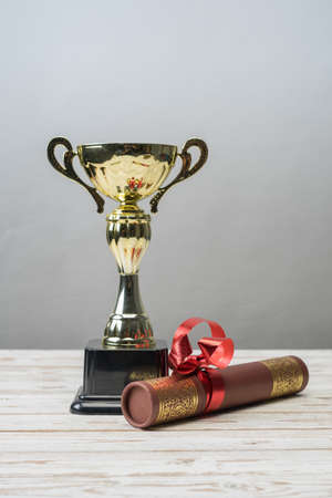 Golden trophy and graduation scroll on white table.Education concept.の写真素材