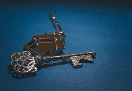 Key and house shape keychain on blue background.Property investment concept.の写真素材