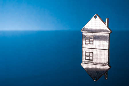 Metal house shape keychain on blue background.の写真素材