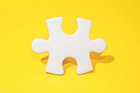 a piece of white puzzle on yellow background.の写真素材