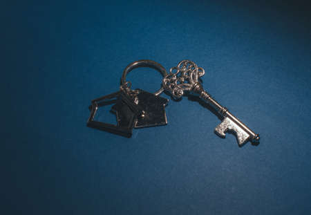 Key and house shape keychain on blue background.Property investment concept.の写真素材