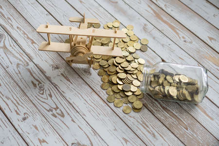 Wooden Airplane toy and jar of coins on vintage wooden table with copy space.Travel concept.の写真素材