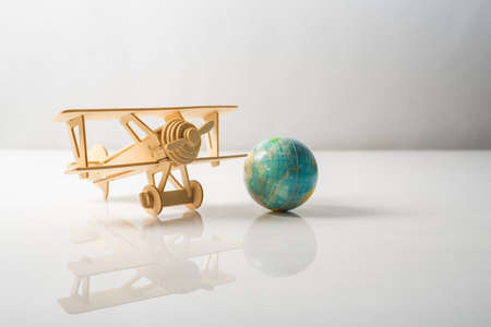 Wooden Aeroplane toy with world globe on white background.Travel Concept.の写真素材