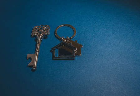 Key and house shape keychain on blue background.Property investment concept.の写真素材