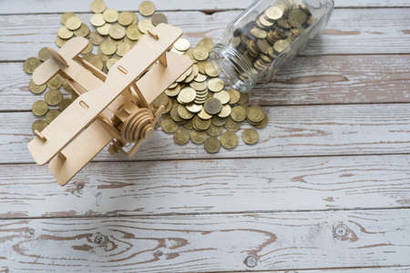 Wooden Airplane toy and jar of coins on vintage wooden table with copy space.Travel concept.の写真素材