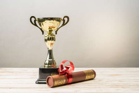 Golden trophy and graduation scroll on white table.Education concept.の写真素材