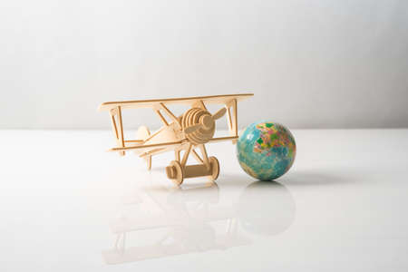 Wooden Aeroplane toy with world globe on white background.Travel Concept.の写真素材