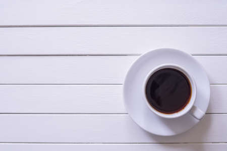 Black coffee in a white cup on white vintage wooden table view from top.Copy space.の写真素材