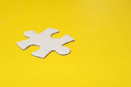 a piece of white puzzle on yellow background.の写真素材