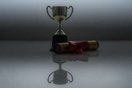 Golden trophy and graduation scroll on white table.Education concept.の写真素材