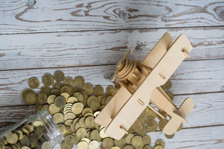 Wooden Airplane toy and jar of coins on vintage wooden table with copy space.Travel concept.の写真素材