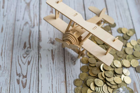 Wooden Airplane toy and jar of coins on vintage wooden table with copy space.Travel concept.の写真素材