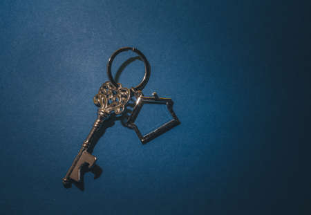 Key and house shape keychain on blue background.Property investment concept.の写真素材