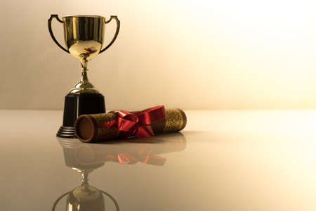 Golden trophy and graduation scroll on white table.Education concept.の写真素材