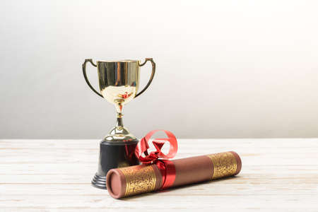 Golden trophy and graduation scroll on white table.Education concept.の写真素材