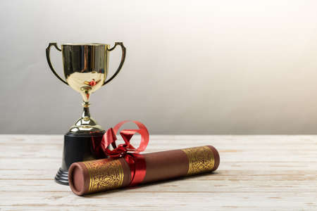 Golden trophy and graduation scroll on white table.Education concept.の写真素材