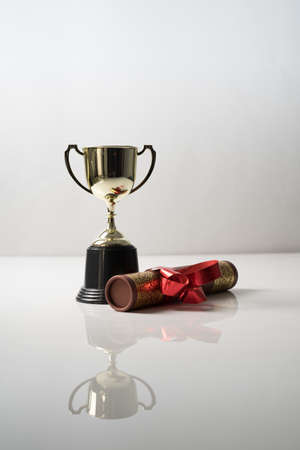 Golden trophy and graduation scroll on white table.Education concept.の写真素材