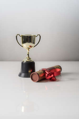 Golden trophy and graduation scroll on white table.Education concept.の写真素材