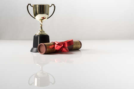Golden trophy and graduation scroll on white table.Education concept.の写真素材