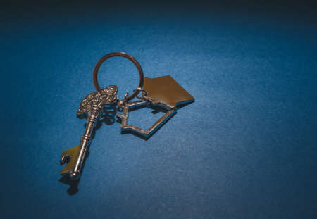 Key and house shape keychain on blue background.Property investment concept.の写真素材