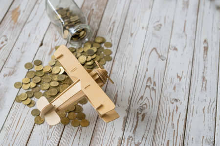 Wooden Airplane toy and jar of coins on vintage wooden table with copy space.Travel concept.の写真素材