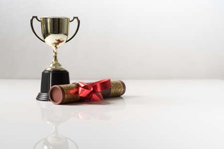 Golden trophy and graduation scroll on white table.Education concept.の写真素材