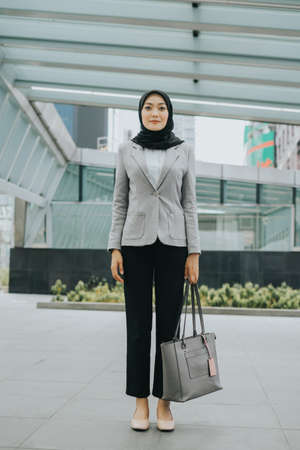 Muslim woman wearing hijab and office attire in the middle of busy city.の写真素材