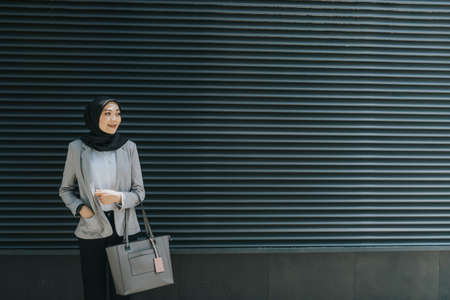 Muslim woman wearing hijab and office attire in the middle of busy city.