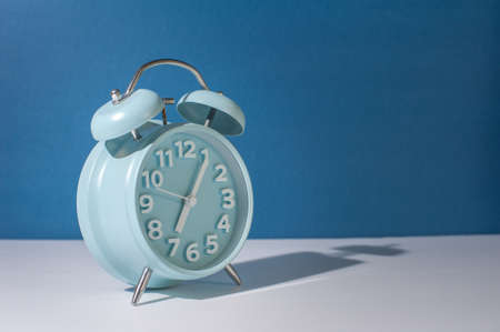 Analog alarm clock on blue background.の写真素材