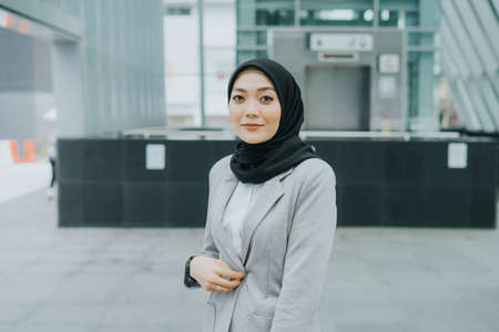 Muslim woman wearing hijab and office attire in the middle of busy city.の写真素材