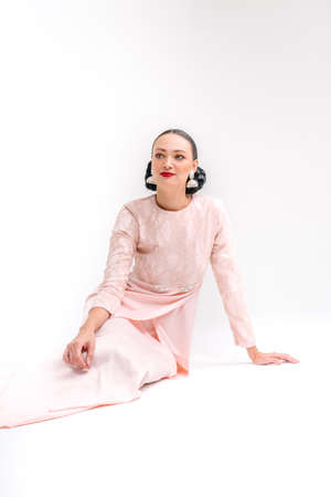 Beautiful girl wearing Asian Malay traditional dress isolate over white background. Modern female fashion for Eid al Fitr celebration or formal event.の写真素材