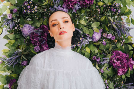 Close up shoot of a beautiful caucassian female model with artificial flower background. Beauty and fashion shoot.の写真素材