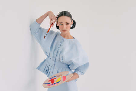 Beautiful girls wearing Asian Malay traditional dress and holding paint brush with blank white canvas isolate over white background.Modern female fashion for Eid al Fitr celebration or formal event.Copy Space.の写真素材
