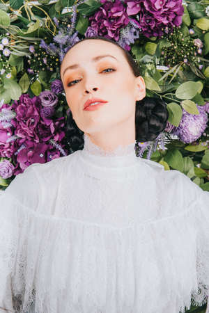 Close up shoot of a beautiful caucassian female model with artificial flower background.Beauty and fashion shoot.の写真素材