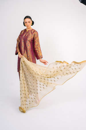 Beautiful female model wearing Asian Malay traditional dress and scarf isolated over white background. Fashion for Muslim Female.の写真素材