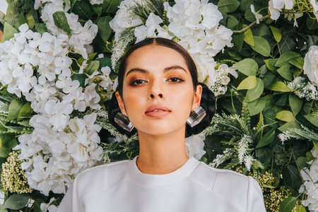 Close up shoot of a beautiful caucassian female model with artificial flower background.Beauty and fashion shoot.の写真素材