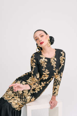 Beautiful girl wearing Asian Malay traditional dress isolate over white background. Modern female fashion for Eid al Fitr celebration or formal event.の写真素材