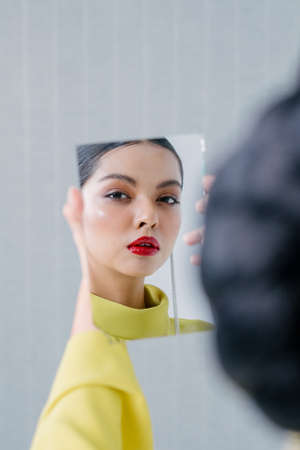 Beautiful girl holding a broken mirror with reflection of her beautiful face.Beauty and fashion shoot.Close up.の写真素材