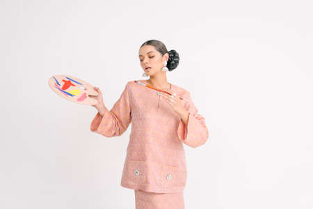 Beautiful girl wearing Asian Malay traditional dress isolate over white background. Modern female fashion for Eid al Fitr celebration or formal event.の写真素材