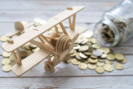 Wooden Airplane toy and jar of coins on vintage wooden table with copy space.Travel concept.の写真素材