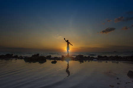 Silhouette of a man with amazing golden sunset view at the beach.の写真素材