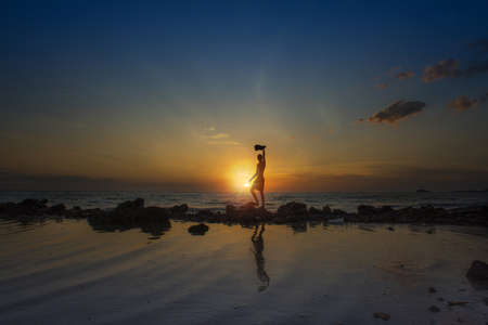 Silhouette of a man with amazing golden sunset view at the beach.の写真素材
