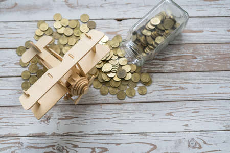 Wooden Airplane toy and jar of coins on vintage wooden table with copy space.Travel concept.の写真素材