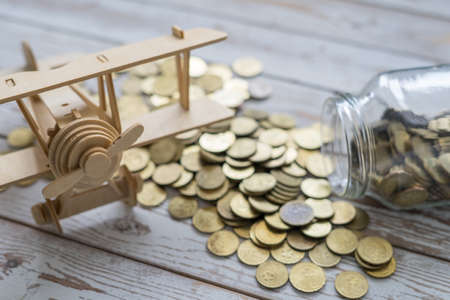 Wooden Airplane toy and jar of coins on vintage wooden table with copy space.Travel concept.の写真素材