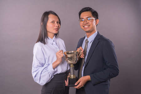 Successful team work.Businessman and woman holding a gold trophy.の写真素材