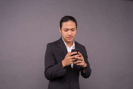 A young business man smiling while using smart phone.の写真素材