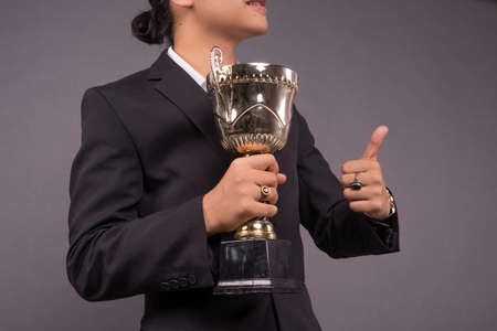 A young business man holding a gold trophy and celebrate his archivement.Close up shotの写真素材