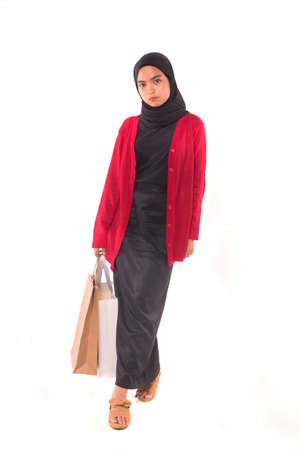 Happy young Muslim girl holding shopping bags isolated over white background.の写真素材